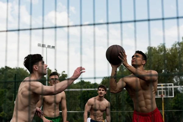 Foco seletivo de desportistas sem camisa jogando basquete na quadra de basquete — Fotografia de Stock