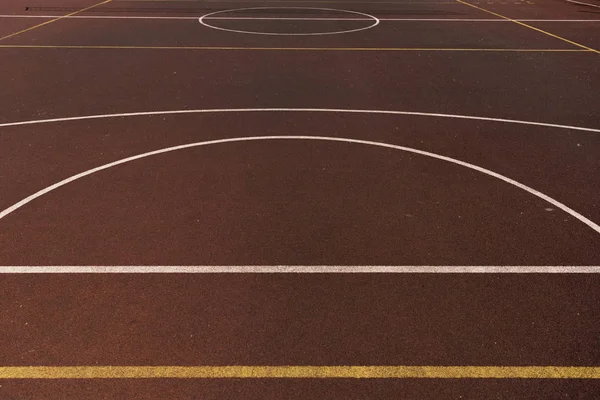 Cancha de baloncesto con líneas amarillas y blancas en la superficie de juego marrón - foto de stock