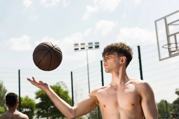 Hemdloser Basketballspieler mit Ball auf dem Basketballplatz bei sonnigem Tag — Stockfoto