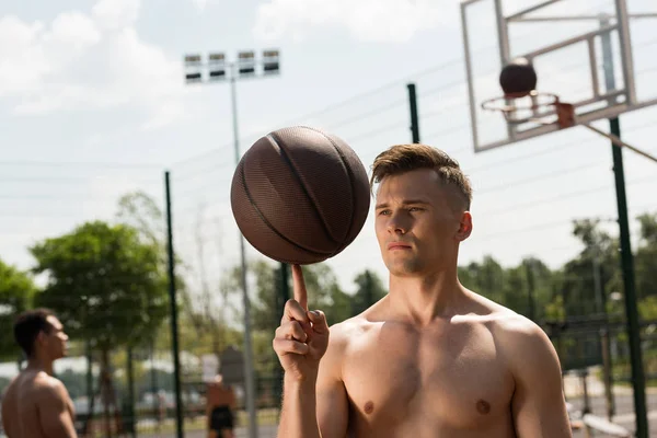 Jogador de basquete sem camisa com bola na quadra de basquete em dia ensolarado — Fotografia de Stock