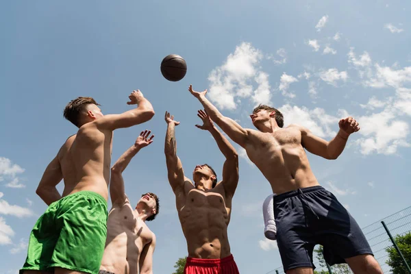 Cuatro deportistas sexy sin camisa jugando baloncesto bajo el cielo azul - foto de stock