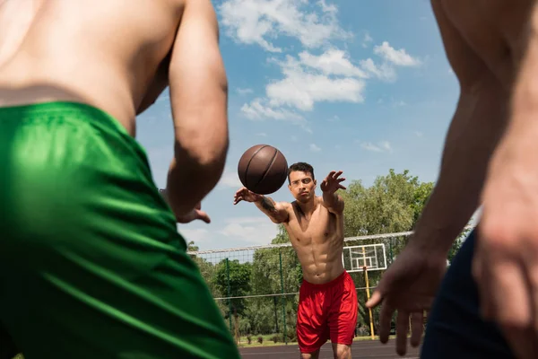 Ausgeschnittene Ansicht von sexy hemdlosen Sportlern, die unter blauem Himmel Basketball spielen — Stockfoto