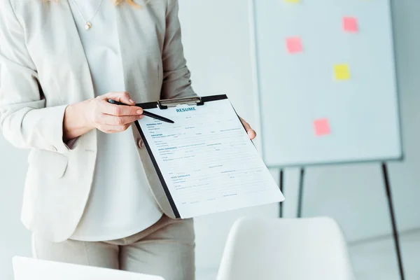 Vista recortada de la mujer sujetando portapapeles con letras de curriculum vitae y pluma - foto de stock