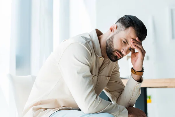 Bello sconvolto uomo seduto e toccare la testa in ufficio — Foto stock