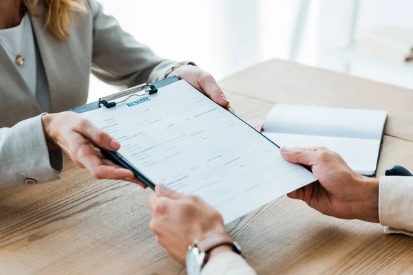 Vista recortada del reclutador dando portapapeles con letras de curriculum vitae al hombre - foto de stock