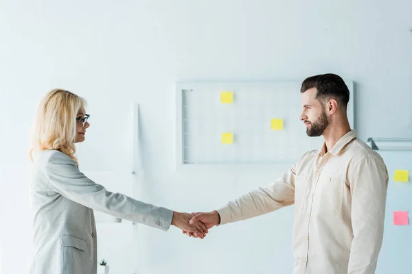 Attractive recruiter in glasses and handsome employee shaking hands — Stock Photo