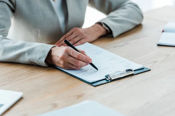 Cropped view of recruiter writing on clipboard with resume letters — Stock Photo