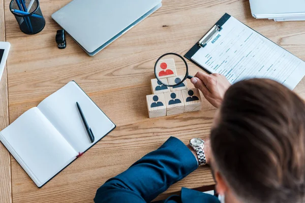 Selective focus of recruiter holding magnifying glass near wooden cubes — Stock Photo