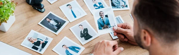 Tiro panorâmico de recrutador escolhendo enquanto segurando foto perto de mesa de madeira — Fotografia de Stock