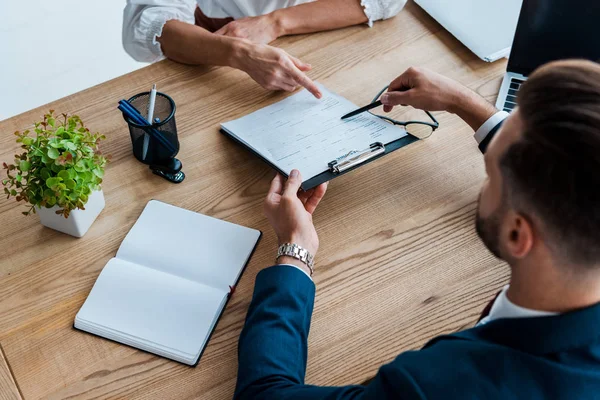 Vue recadrée de l'employé pointant du doigt vers le presse-papiers près du recruteur — Photo de stock