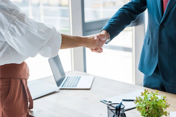 Vista recortada del empleado y reclutador estrechando la mano en la oficina - foto de stock