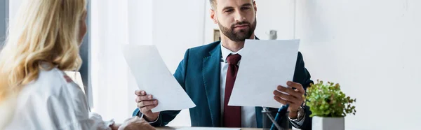 Panoramic shot of bearded recruiter holding papers near blonde employee — Stock Photo
