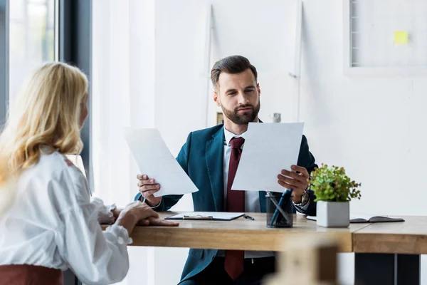 Selective focus of bearded recruiter holding papers near blonde employee — Stock Photo