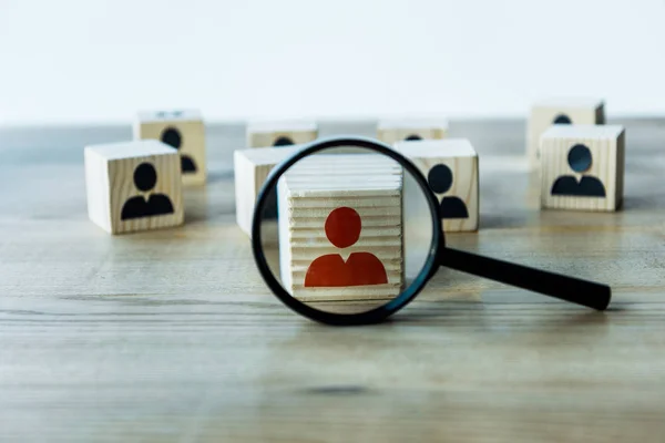 Selective focus of magnifying glass near cubes on wooden desk — Stock Photo