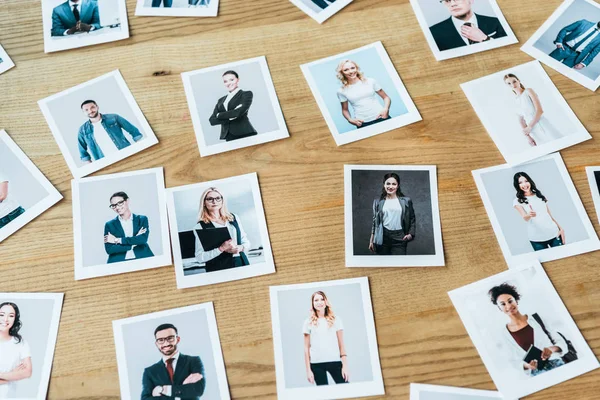 Photos with men and women employees on wooden table — Stock Photo