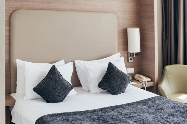 Bed with pillows and cushions in cozy hotel room — Stock Photo
