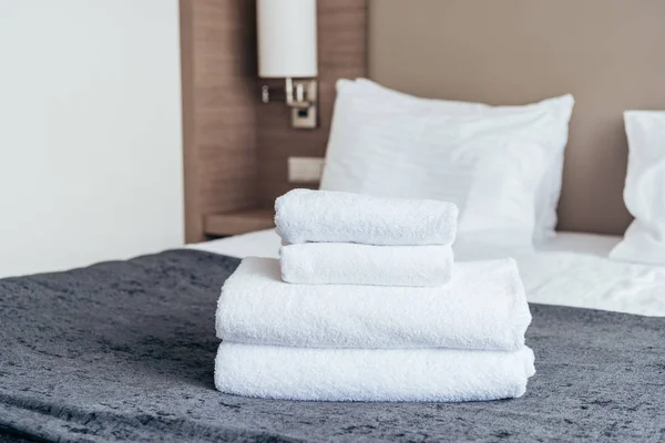 Toalhas brancas dobradas na cama no quarto do hotel — Fotografia de Stock