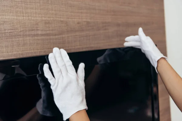 Partial view of maid in white gloves touching tv iwith blank screen n hotel room — Stock Photo