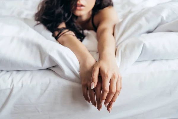 Selektiver Fokus der sinnlichen brünetten jungen Frau, die auf dem Bett liegt — Stockfoto