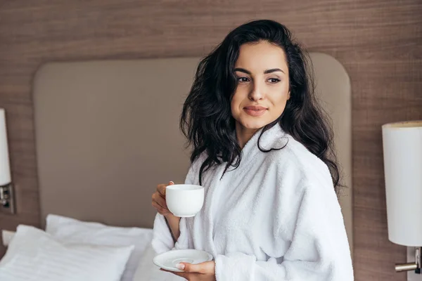 Attraente giovane donna in bagno bianco in possesso di tazza di caffè al mattino in camera da letto — Foto stock