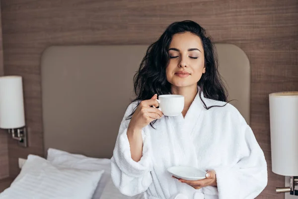 Attraente giovane donna in bagno bianco in possesso di tazza di caffè al mattino in camera da letto — Foto stock