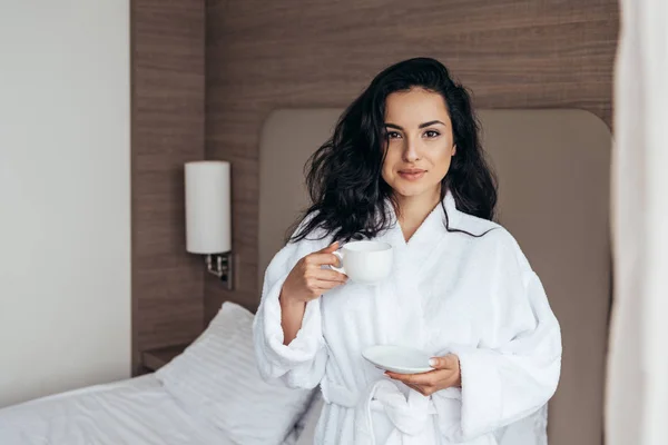 Jovem atraente no banheiro branco segurando xícara de café de manhã no quarto — Fotografia de Stock