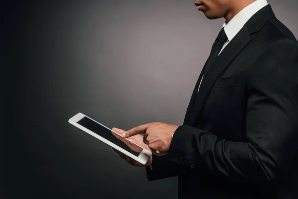 Vista parcial del hombre de negocios afroamericano usando tableta digital sobre fondo oscuro - foto de stock