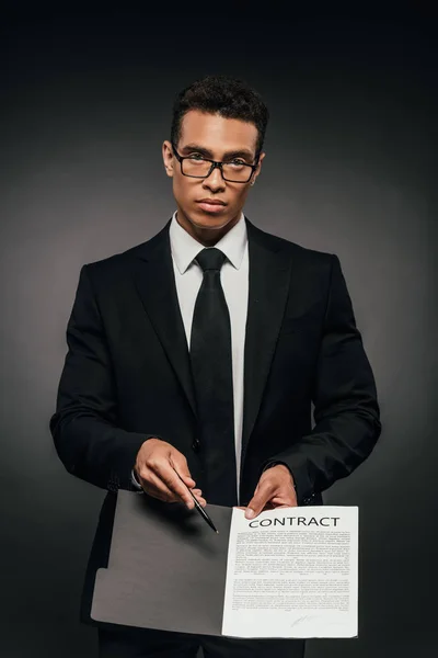 Афроамериканець бізнесмен показує контракт на темному фоні — стокове фото