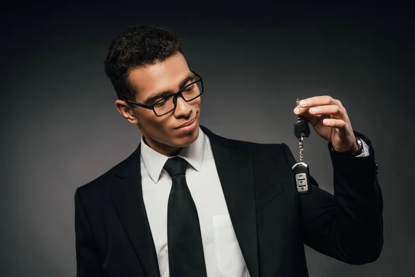 Африканский американский бизнесмен смотрит на ключи от машины на темном фоне — стоковое фото