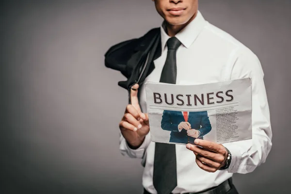 Обрізаний вид афроамериканського бізнесмена, який тримає блістер і ділову газету на темному фоні — стокове фото