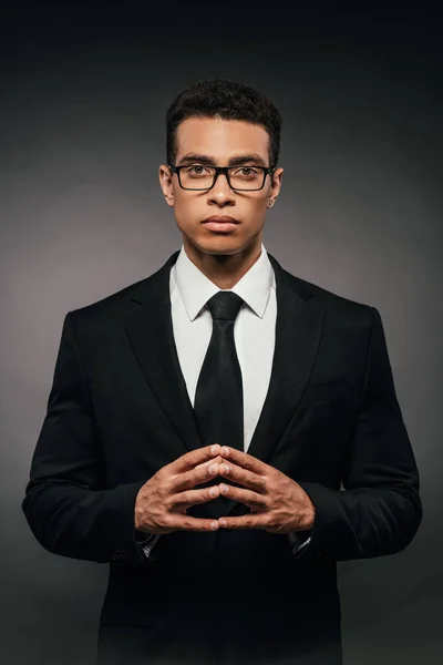 Exitoso hombre de negocios afroamericano en traje y gafas sobre fondo oscuro - foto de stock