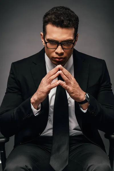 Tenso hombre de negocios afroamericano en traje y gafas sobre fondo oscuro - foto de stock