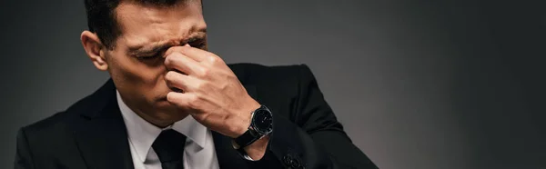 Tired african american businessman in suit rubbing his eyes on dark background, panoramic shot — Stock Photo