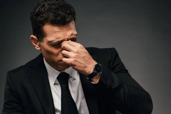 Tired african american businessman in wristwatch rubbing his eyes on dark background — Stock Photo