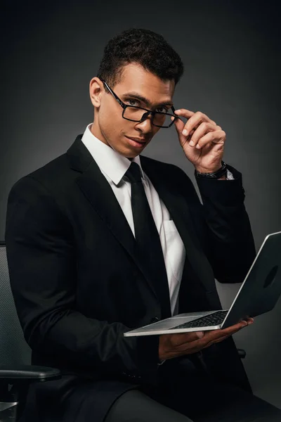 Successful african american businessman holding laptop on dark background — Stock Photo