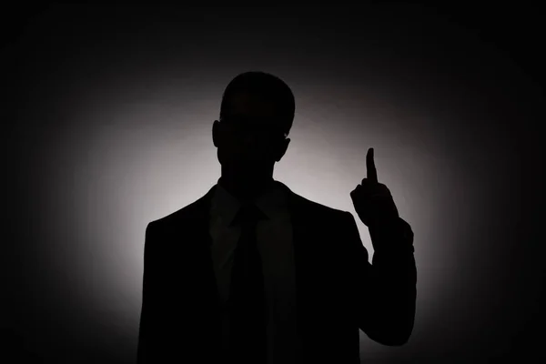 Чорний силует бізнесмена, що показує знак ідеї з заднім світлом — Stock Photo
