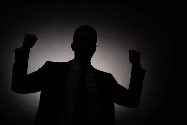 Чорний силует бізнесмена, що показує так жест із заднім світлом — стокове фото