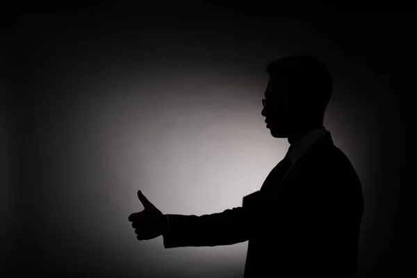 Side view of black silhouette of businessman  showing thumb up with back light — Stock Photo