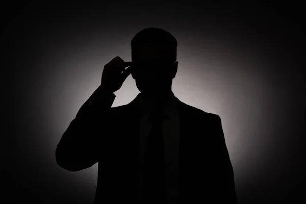 Silueta negra de hombre de negocios en gafas con luz de fondo - foto de stock