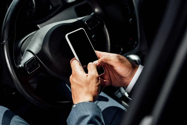 Partial view of african american businessman in suit using smartphone in car at sunny day — Stock Photo