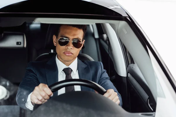 Homme d'affaires afro-américain en costume et lunettes de soleil voiture de conduite — Photo de stock