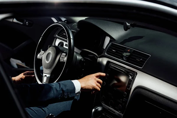 Cropped view of african american businessman in suit pushing button in car — Stock Photo