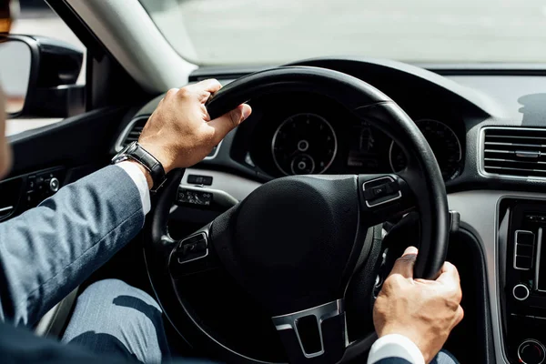 Vista parcial del hombre de negocios afroamericano en traje de conducir coche - foto de stock