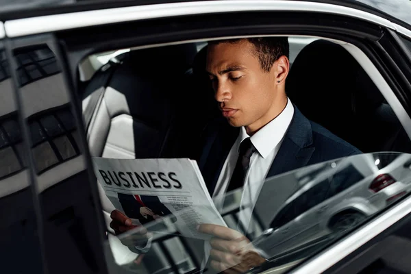 Africano americano empresário em terno leitura jornal no carro — Fotografia de Stock