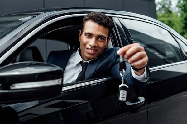 Hombre de negocios afroamericano feliz sosteniendo llaves del coche - foto de stock