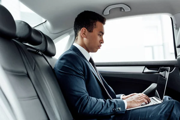 Side view of african american businessman using laptop in car — Stock Photo