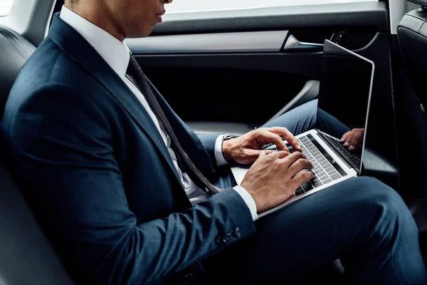 Ausgeschnittene Ansicht eines afrikanisch-amerikanischen Geschäftsmannes mit Laptop im Auto — Stockfoto