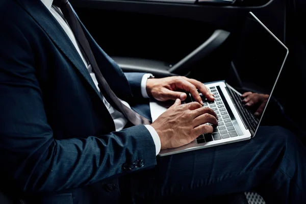 Vue partielle de l'homme d'affaires afro-américain en utilisant un ordinateur portable en voiture — Photo de stock
