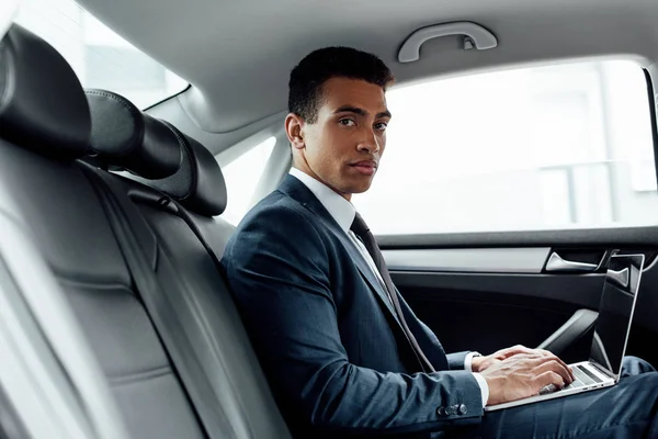 Handsome african american businessman using laptop in car — Stock Photo