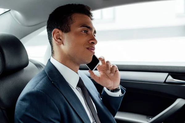Красивий усміхнений афроамериканський бізнесмен говорить на смартфоні в машині — стокове фото